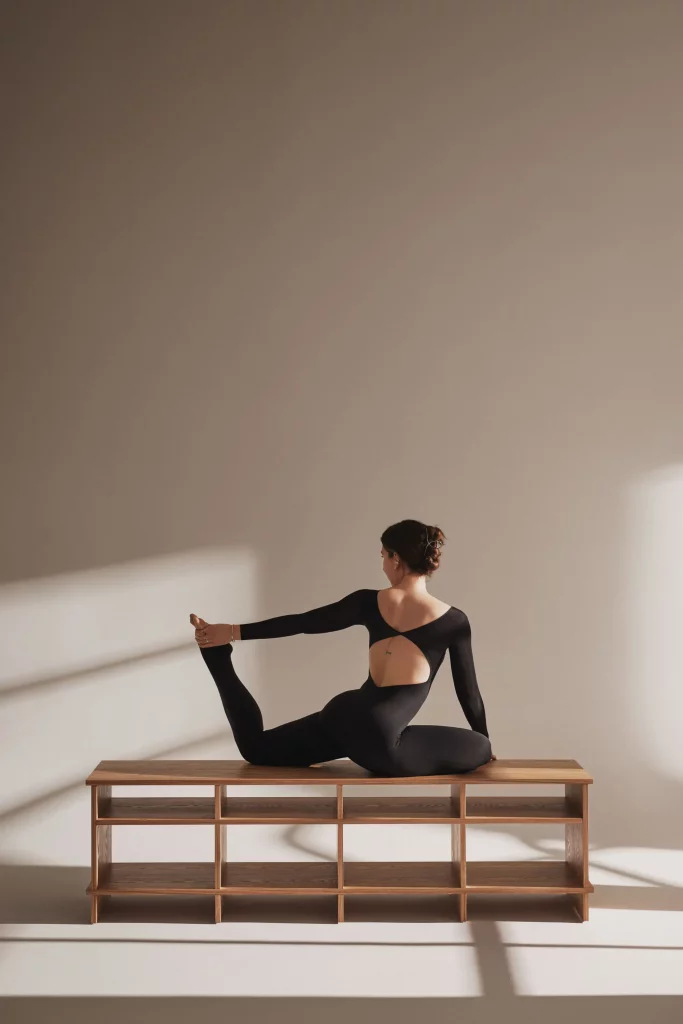 profesora de yoga posada sobre mueble de diseño