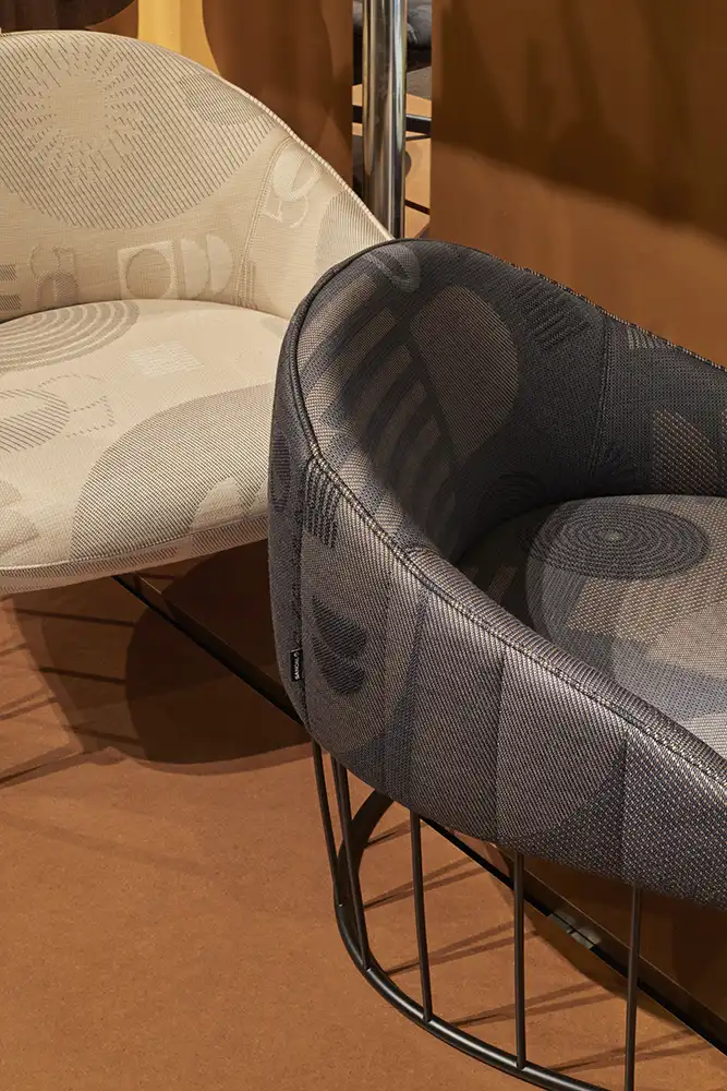 Captura fiel de materiales y acabados en expositor de diseño. Detalle de mobiliario de diseño moderno expuesto en el stand de Sancal en Feria Valencia, con sofás y mesas sobre suelo de hormigón pulido.